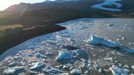 aerial tilt up revealing glacier lake landscape with scattered iceberg