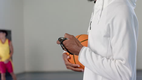 African-American-coach-holds-a-basketball-indoors,-with-copy-space