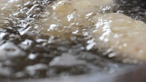 close-up of halloumi cheese on stick immersed in boiling oil