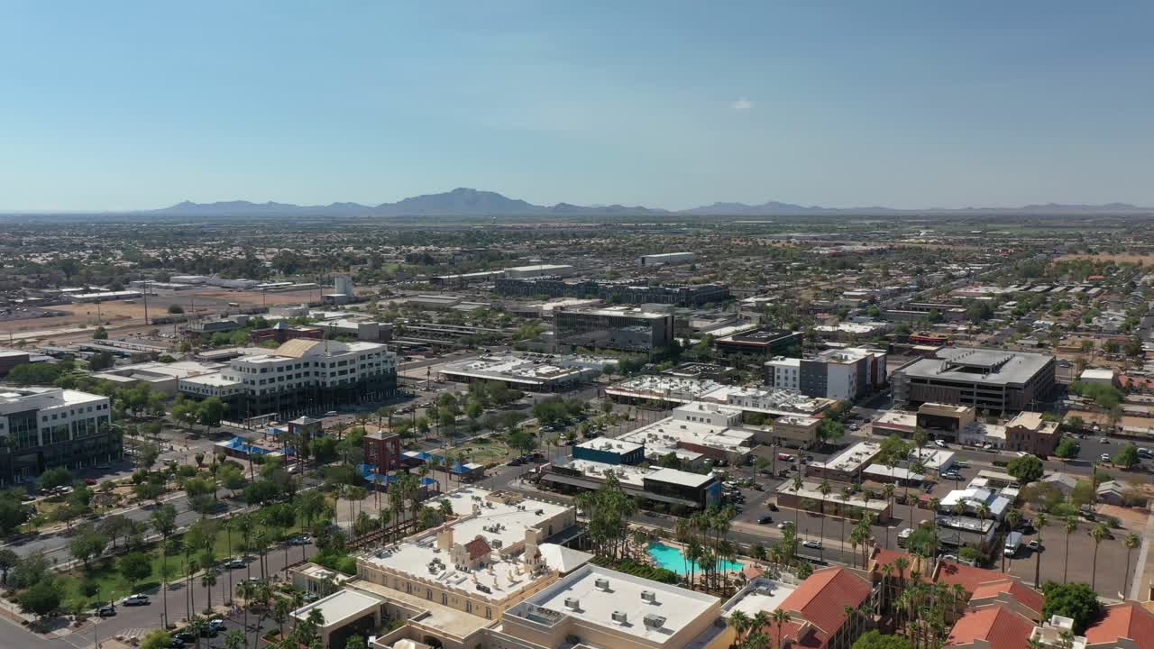 piscina y palmeras en la punta de flecha en la ciudad de chandler, ee.uu. conduciendo coches en la calle principal a lo largo de las palmeras. pájaros aéreos tiro de ojo ancho.