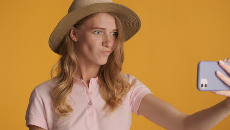 mujer caucásica con un sombrero haciendo una llamada de video en el teléfono inteligente.