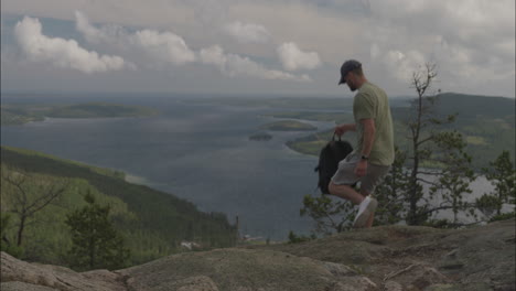 young man with backpack hiking on hilly terrain of scandinavia, back view