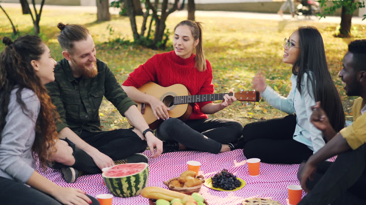 Friends enjoying a picnic in the park with music and guitar