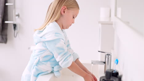 child washing hands in bathroom