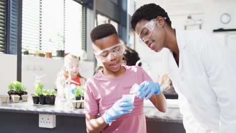 diverse female teacher and happy schoolchildren having science class in school lab