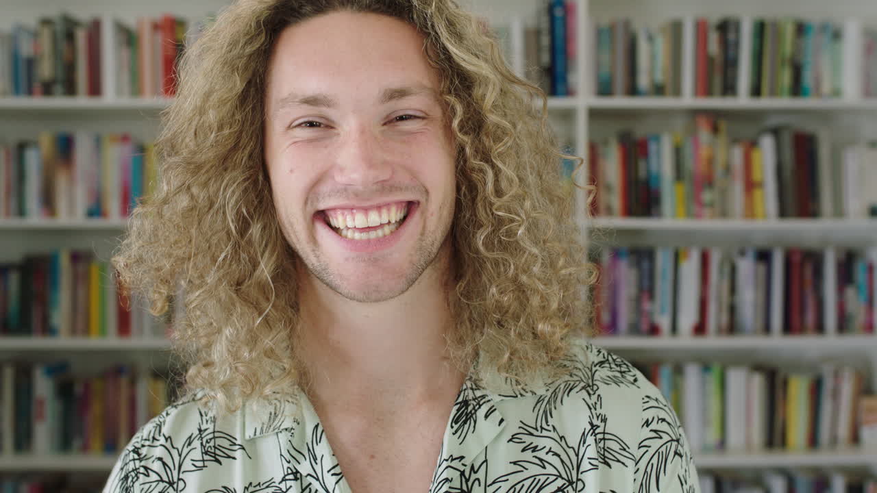 retrato de un joven estudiante sonriendo estantería biblioteca universidad