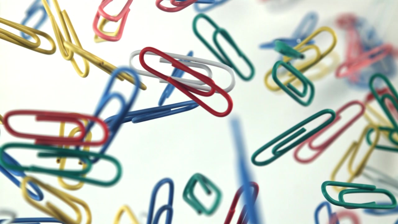 Colorful Paper Clips Floating and Scattered on a White Background