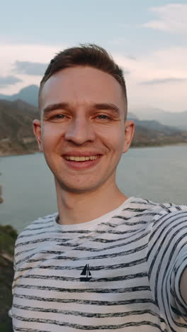 man posing in front of a lake and mountains