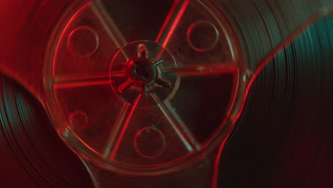 rotating reels of retro tape recorder in red and blue light