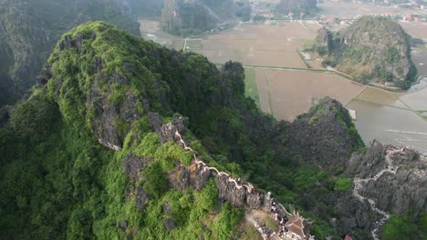 aerial orbiting around lying dragon statue on top of limestone mountain at mua cave viewpoint in ninh binh vietnam at sunset