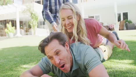 happy caucasian couple with son playing and lying in garden