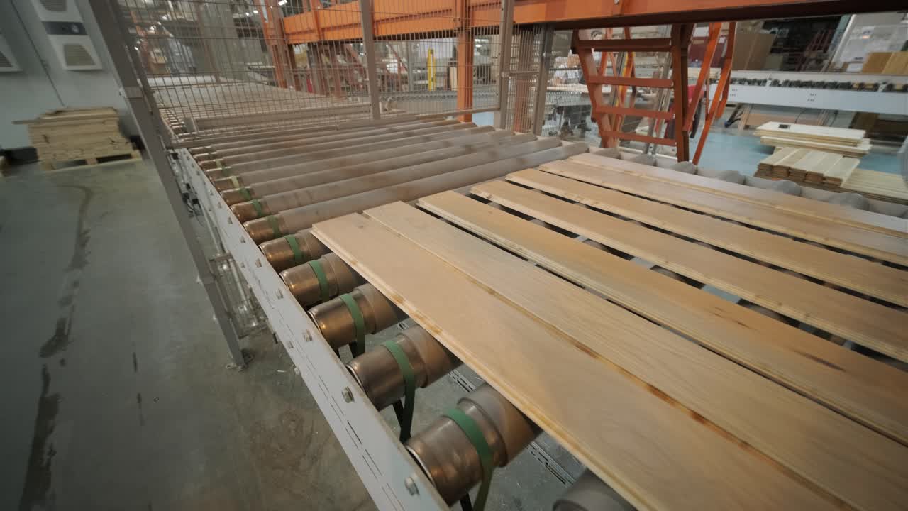 Assi di legno che si muovono su un nastro trasportatore automatizzato in una fabbrica.