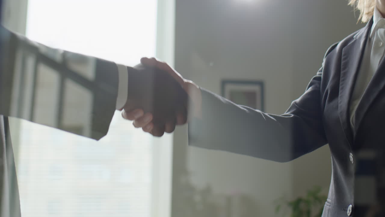 Stretta di mano tra partner commerciali dietro la parete di vetro di un ufficio