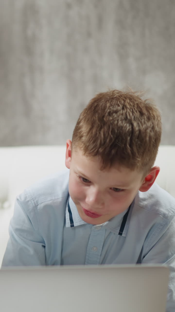 Native speaker English teacher and happy primary school pupil watch and discuss educative video via laptop computer at home lesson slow motion