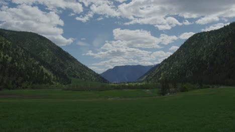 Lapso-De-Tiempo-De-4k-De-Campo-Con-Montañas-Con-Campos-Verdes,-Nubes-Blancas-Y-Rancho