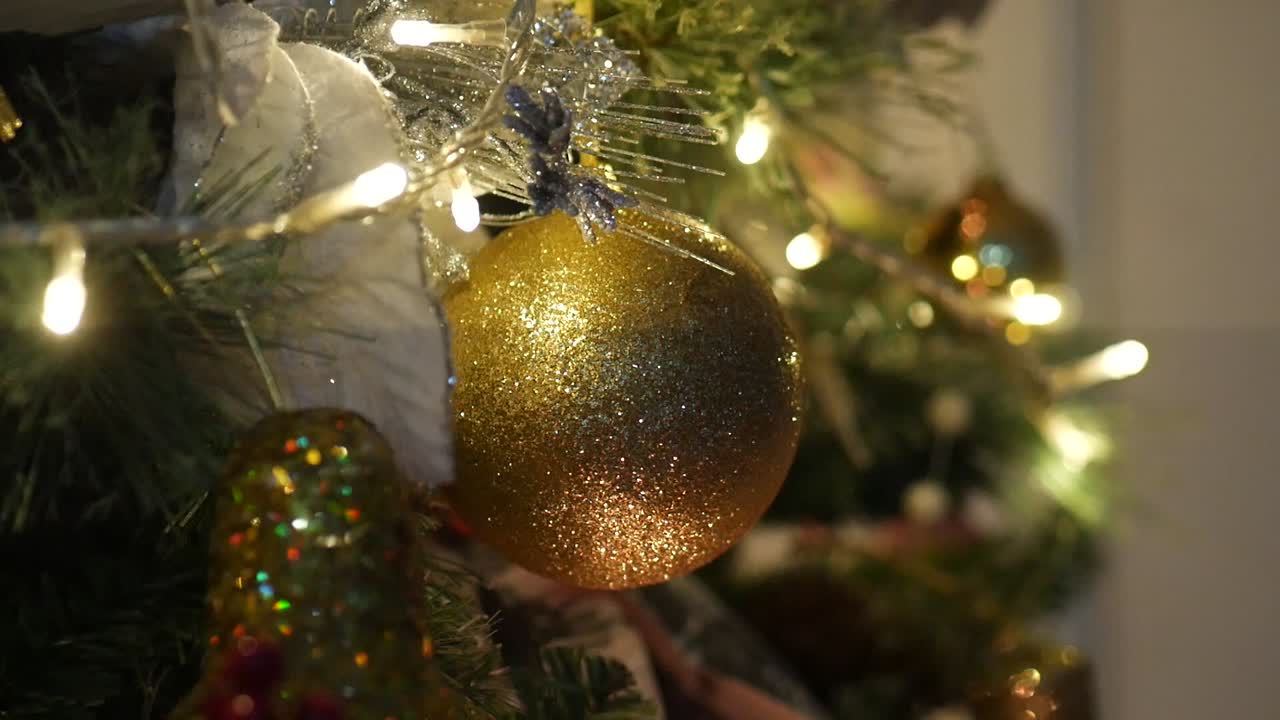 primer plano de adornos navideños dorados brillantes en un árbol de navidad iluminado