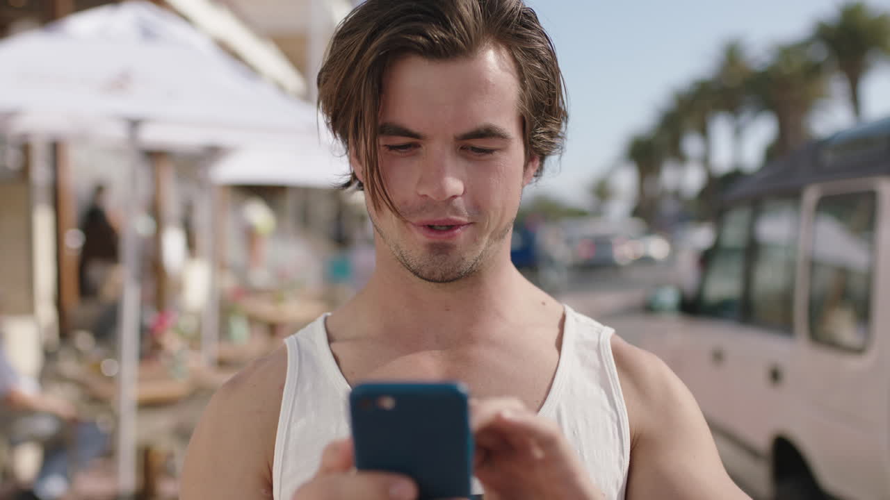 ritratto di un giovane attraente che usa il telefono su una spiaggia trafficata