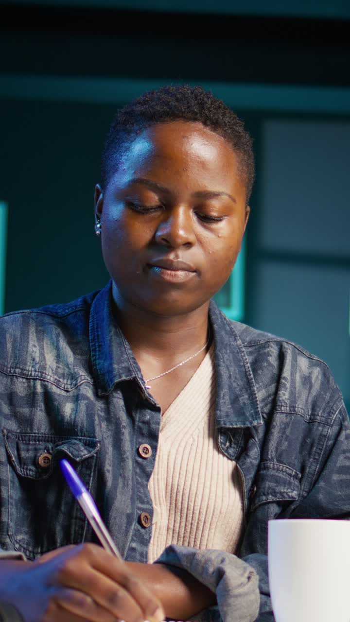 Vertical video Portrait of smiling woman sitting on chair at home office desk, writing notes