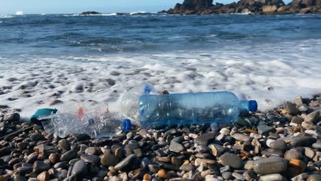 ocean waves wash plastic pollution onto a rocky shoreline