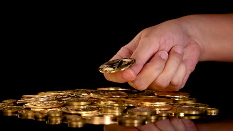 human hand flips golden digital coin onto stack of coins, dramatic lighting, black background