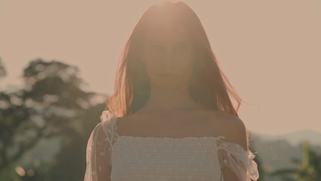 Giovane donna in piedi all'aperto con controluce dell'ora d'oro.