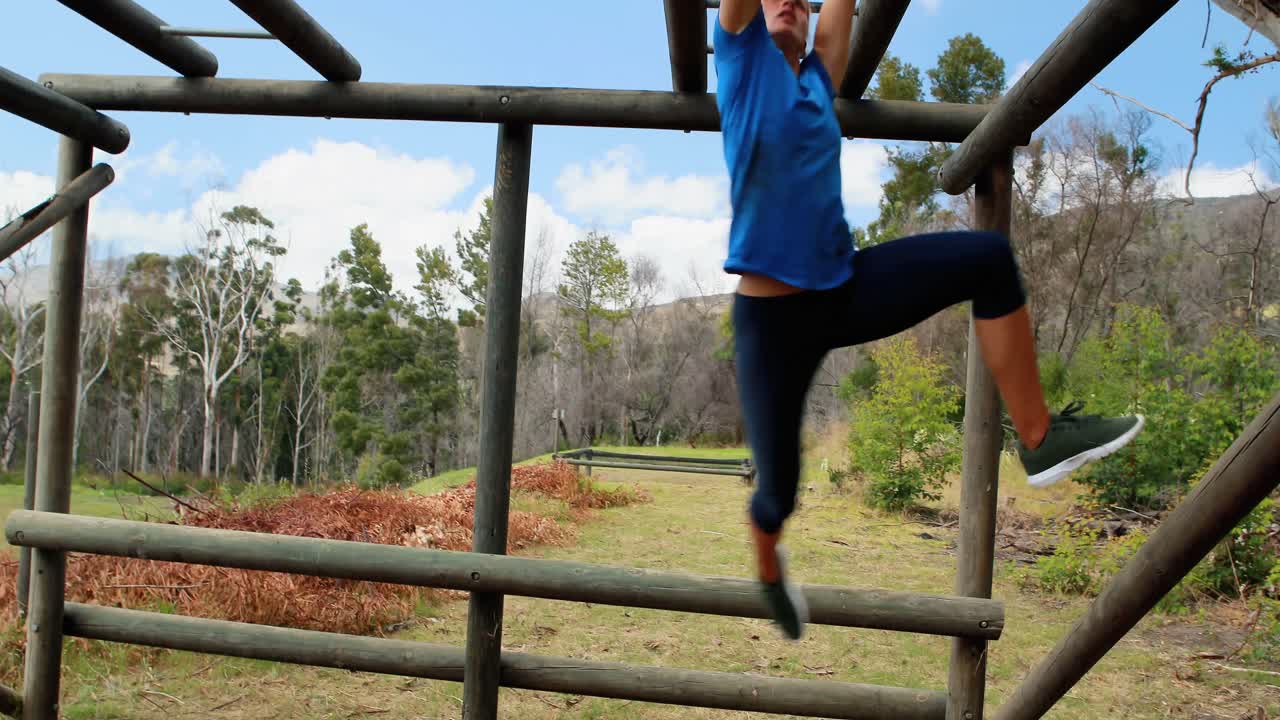 hombre y mujer en forma escalando barras de mono durante una carrera de obstáculos