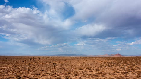 A-fast-moving-aerial-hyper-lapse-over-the-Mojave-desert,-Joshua-trees-and-a-flat-basin-with-mountains-in-the-distance