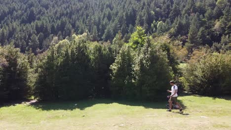 hiker orienting himself with a mobile app through pine trees in the pyrenees