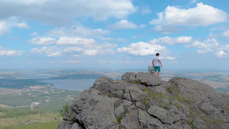 young hiker walking along an impressive mountains cliff. lakes on background