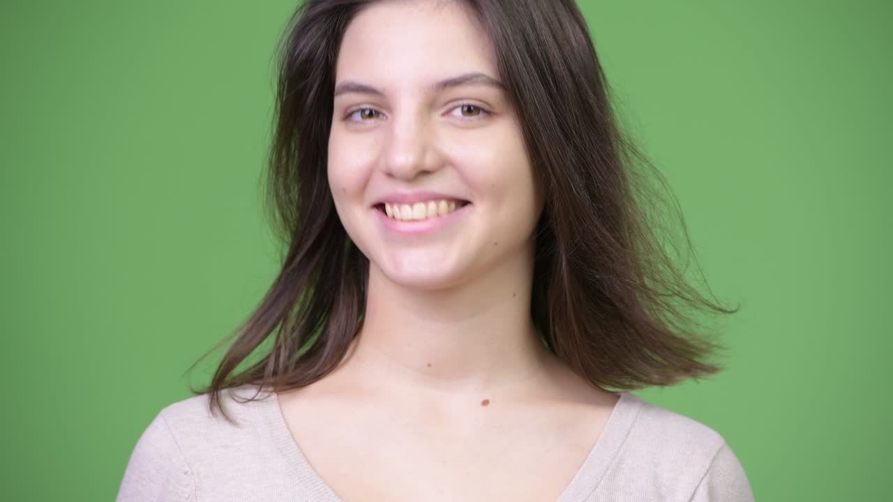 joven hermosa asintiendo con la cabeza sí contra el fondo verde