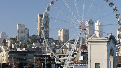 rueda de la ferris conocida como rueda skystar con rascacielos de la ciudad y apartamentos en el fondo, san francisco, estados unidos