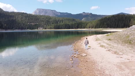 woman walks around black lake at zabljak, durmitor national park, montenegro