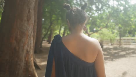 the camera follows a girl in a dress with partially exposed back and hair tied in small ponytails