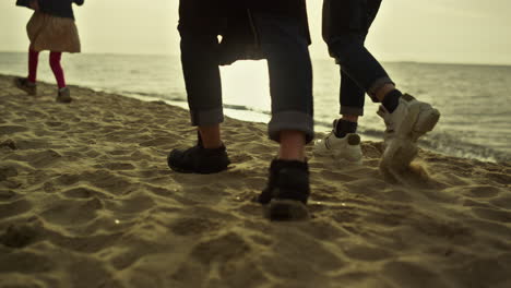 People-legs-stepping-beach-at-sunset-sea-nature.-Family-walking-sandy-coast.