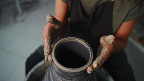 woman shaping a vase on a pottery wheel