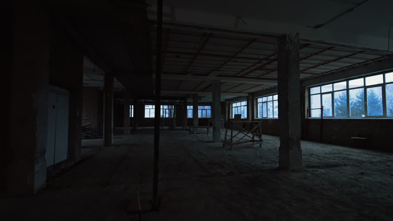 Large room with big windows and columns. Building at construction with unfinished walls, ceiling and floors.