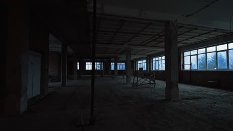 large room with big windows and columns. building at construction with unfinished walls, ceiling and floors.