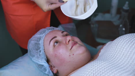 beautician prepares and applies alginate mask to woman