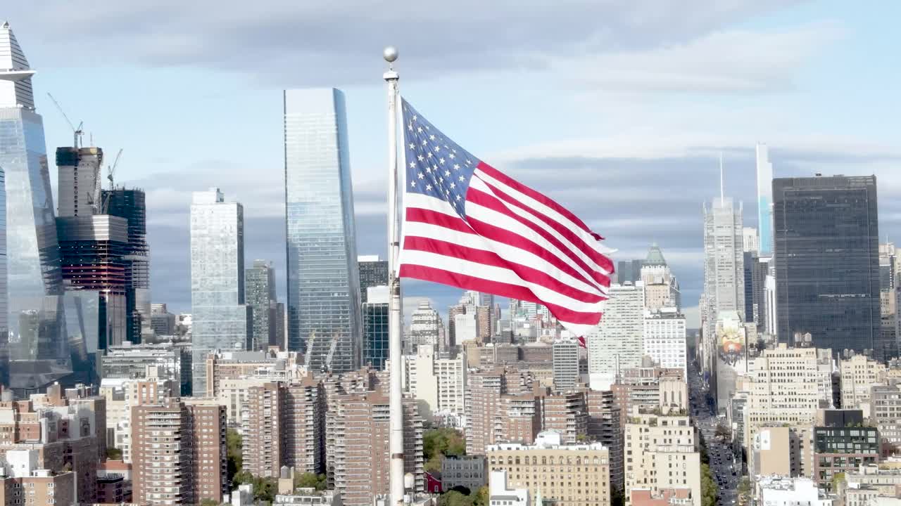 órbita aérea de la bandera de estados unidos ondeando en el viento con midtown y hudson yards en el fondo