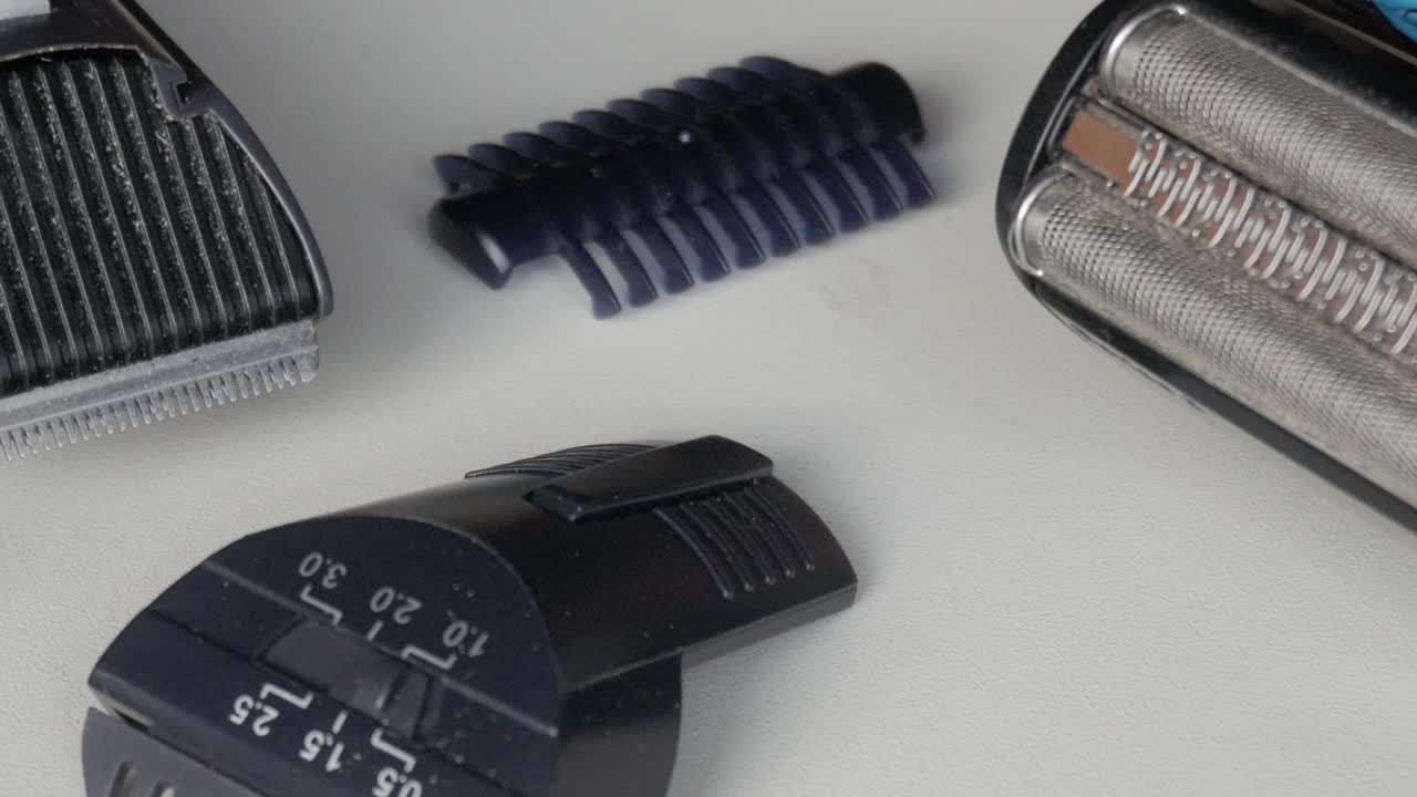 Macro view of an electric shaving kit showing razor blades and trimmer attachments arranged on a white background