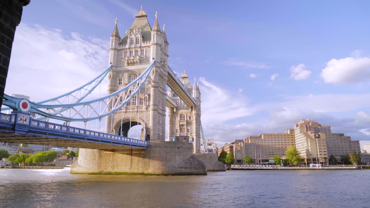 Smooth reveal of Tower Bridge in London by river Thames on a sunny summer day with blue sky and light clouds