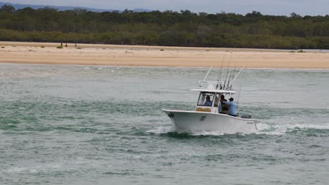 a speedboat moves swiftly by a sandy beach