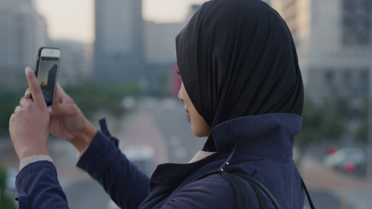 portrait young muslim woman tourist using smartphone taking photos of city photographing urban cityscape enjoying sharing travel experience smiling happy