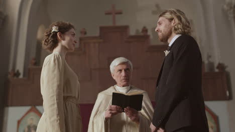 young couple having wedding ceremony in christian church