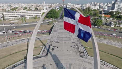 aerial view of waving flag of dominican republic at plata de la bandera and cityscape of santo domingo in background