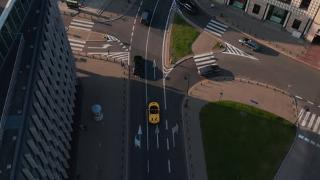 Birds-eye-view-of-cars-driving-in-street-of-city.-Tracking-of-yellow-convertible-sports-car-in-old-town.-Warsaw,-Poland
