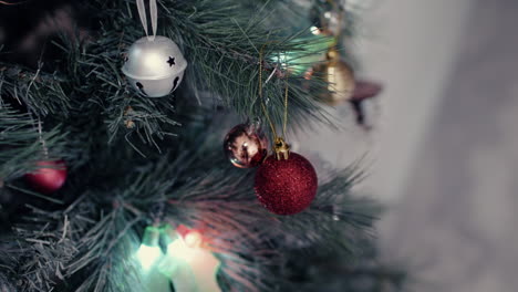 colorful christmas baubles, holly leaf, and ornament lights around christmas tree