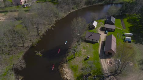 aerial top down view of kayaks and paddle boats reaching the riverbank during the võhandu rowing marathon. paddler teams land and exit onto the shore, carrying kayaks over land. competition coverage