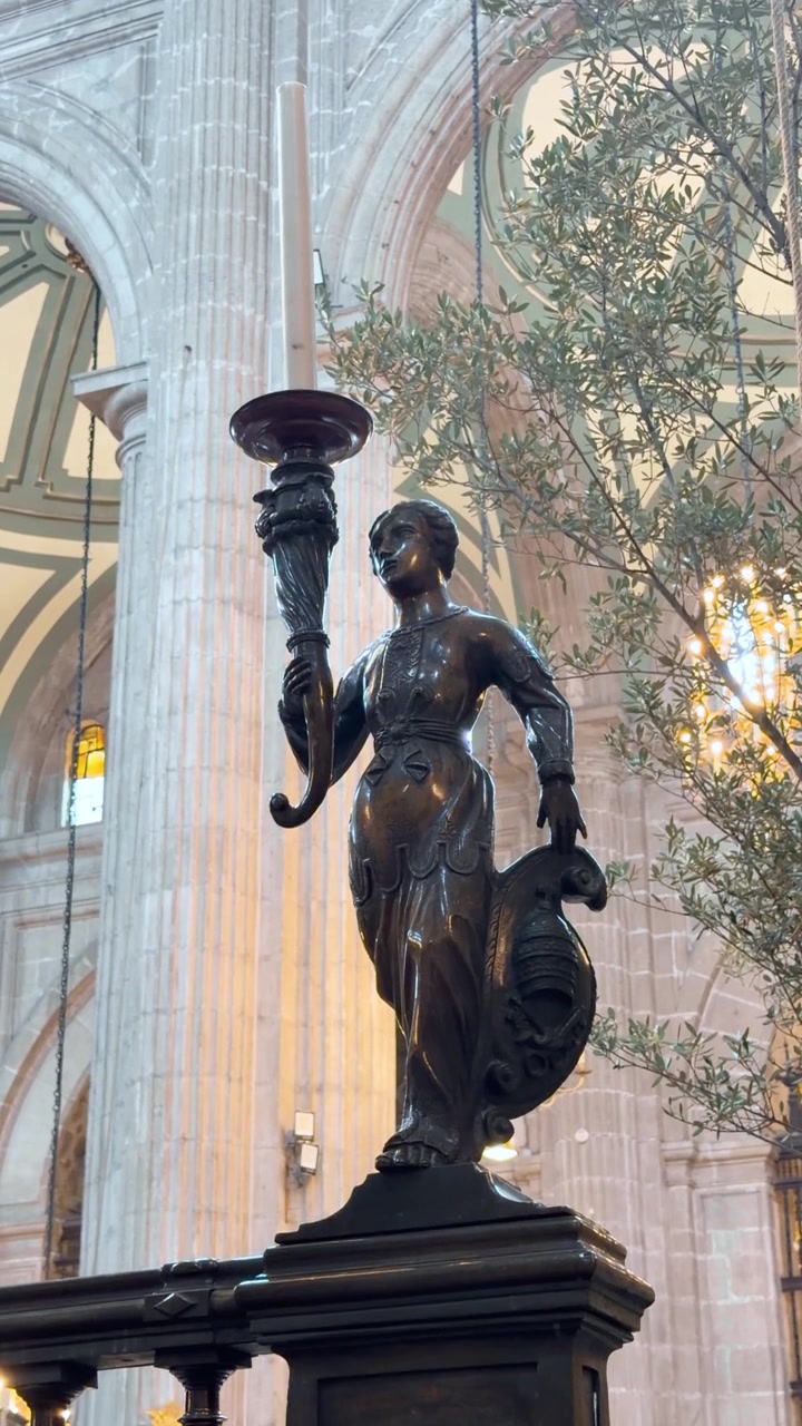 Statua di candelabro in bronzo si erge nell'interno ornato della navata della Cattedrale di Città del Messico