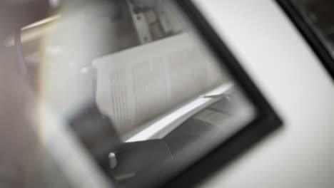 close up shot of conveyor, production line of printed pages on the printing line, looking through the window